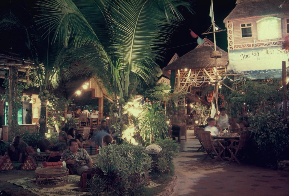 Torch-lit courtyard seating with floor cushions at Drop In in the evening