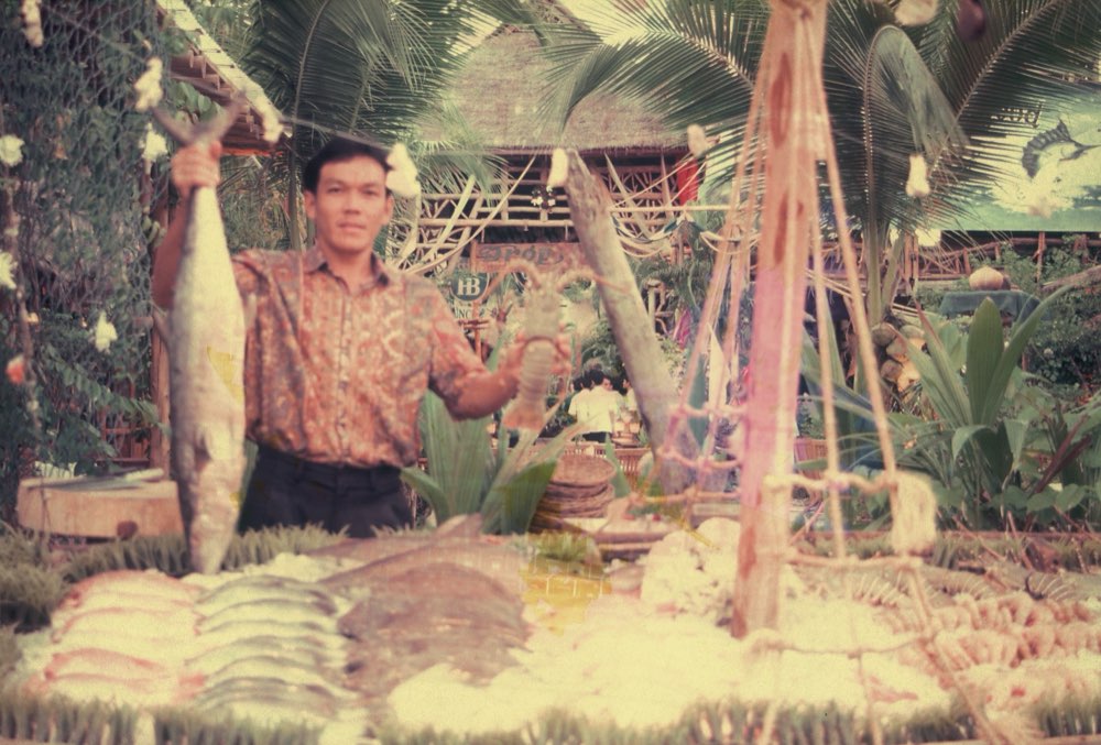 A Drop In team member holding up fresh fish and lobster at the seafood display