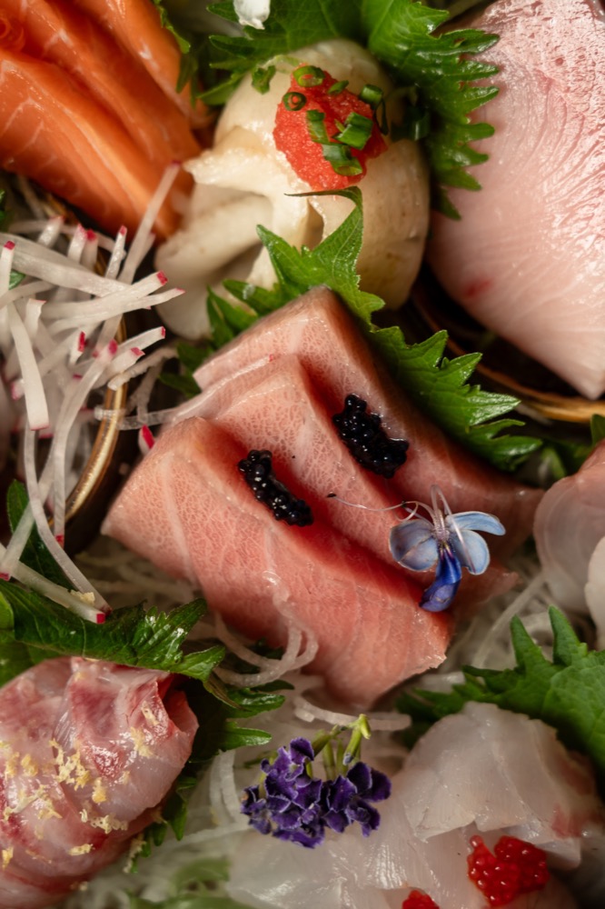 Close-up of sashimi plated with caviar and edible flowers at BABOU