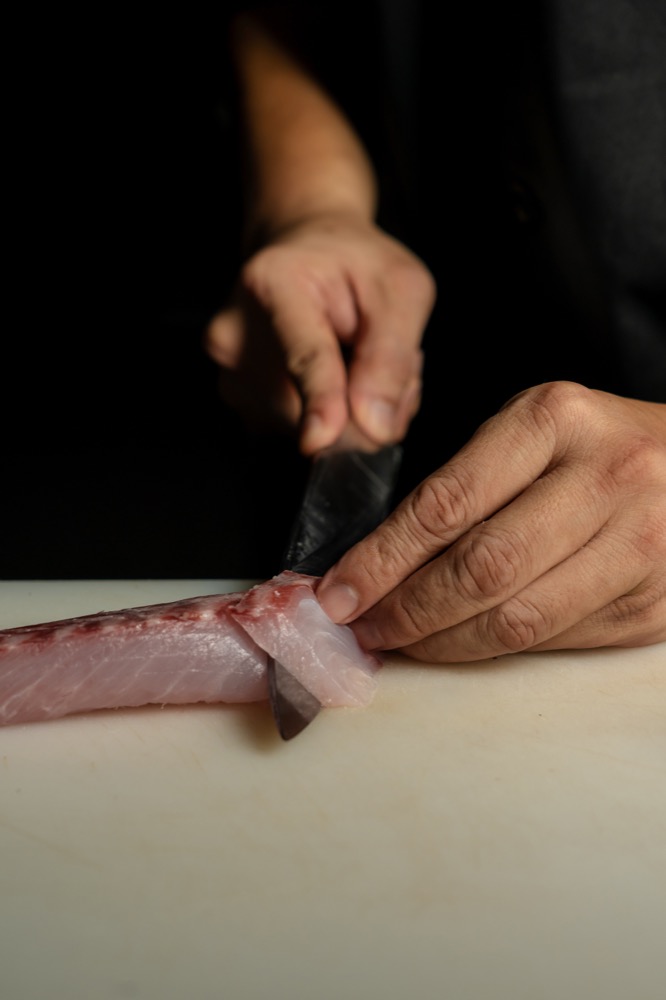 Close-up of a knife slicing fresh fish at BABOU's Raw Bar