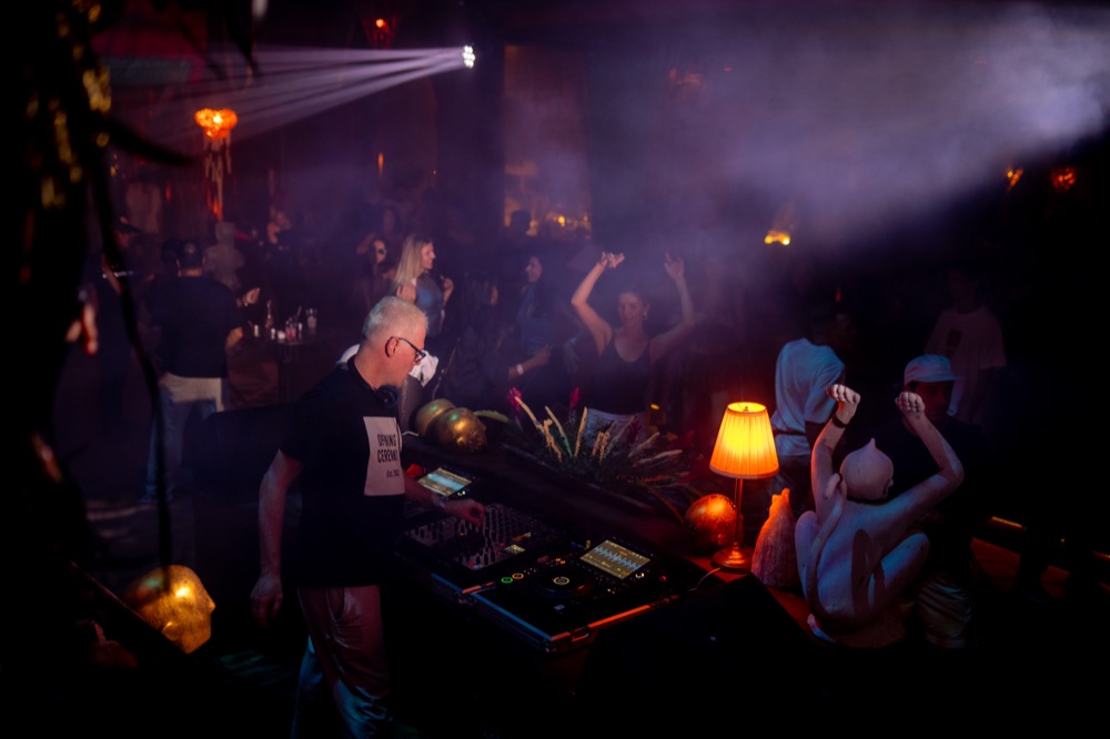 DJ performing for a crowd at BABOU's Club, lit in purple haze